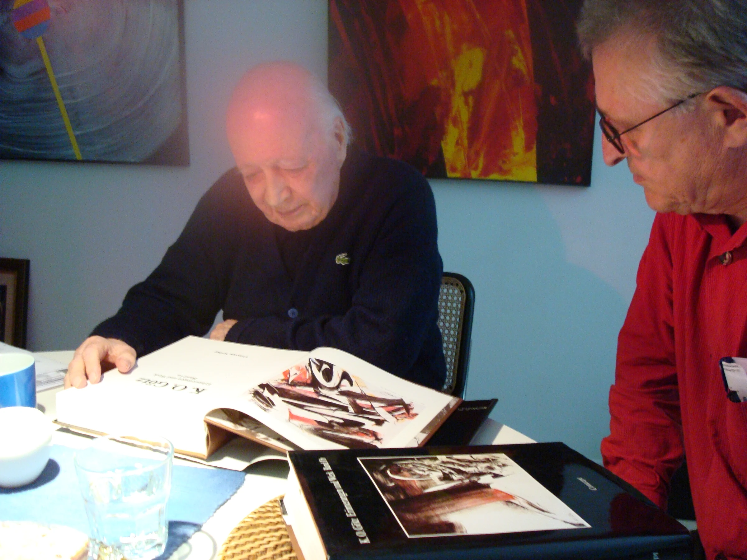 Hilko Weerda und K. O. Götz betrachten gemeinsam ein aufgeschlagenes Kunstbuch.