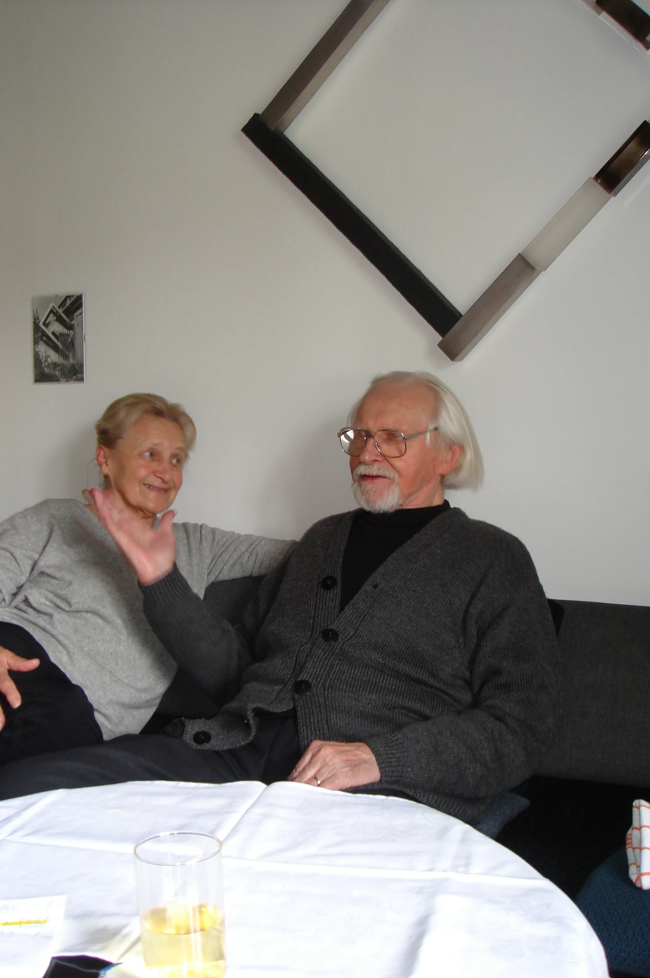 Paul Reich und eine Begleiterin im Gespräch, mit einer Skulptur an der Wand.